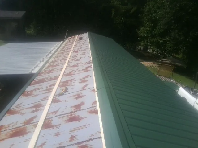 Old rusted panels beside newly installed green metal roofing — Wind Damage Roof Repair by Roofing Brothers in Attleboro