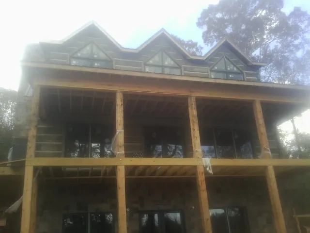 Dormers and porch framing on a large log home under construction — Roof Coating work by our crew in Attleboro