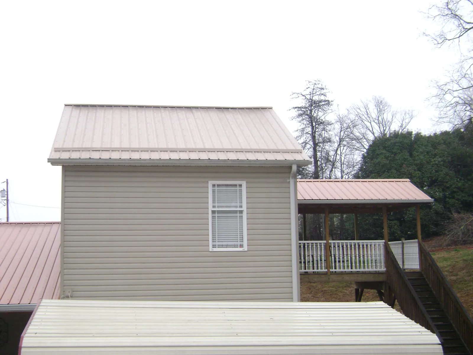 Tan metal roofs on a two story addition and attached porch, from a Roof Replacement job in Attleboro